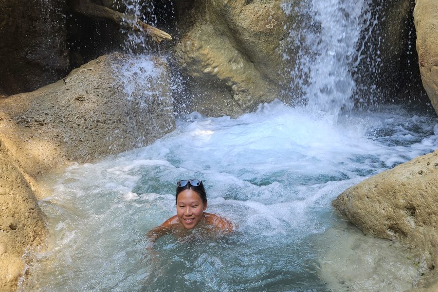 Alyssa swimming under a waterfall